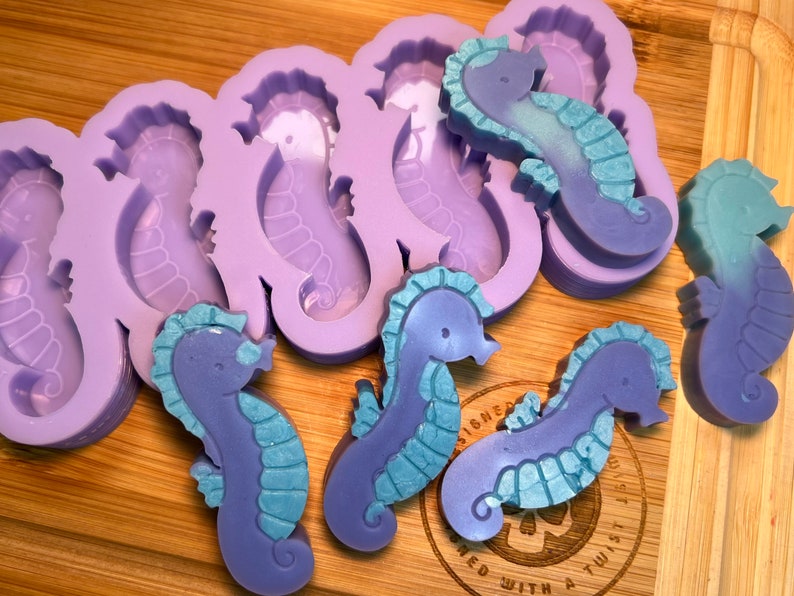 May include: Purple and blue silicone mold with multiple seahorse shapes.  The mold is filled with purple and blue seahorse-shaped soaps.