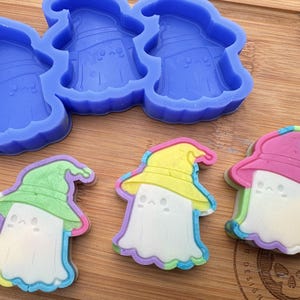 May include: Four silicone molds shaped like ghosts wearing witch hats, with four finished soap bars in the same shape, each with a different color scheme of pink, yellow, green, and blue.