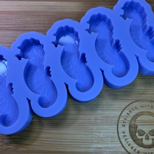 May include: Purple silicone mold with six seahorse shapes. The mold is designed with a detailed seahorse outline in each cavity.