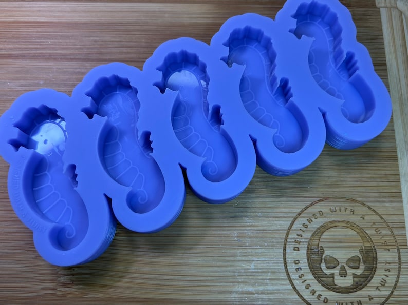 May include: Purple silicone mold with six seahorse shapes. The mold is designed with a detailed seahorse outline in each cavity.