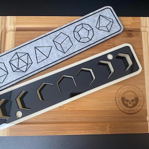 May include: Two wooden cutting boards with a gray and black design. The top board has a gray background with black geometric shapes. The bottom board has a black background with white geometric shapes. The boards are both rectangular and have rounded corners. The text "Created with a Twist" is engraved on the bottom board.