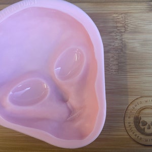 Peut inclure: Moule en silicone rose en forme de tête d'extraterrestre. Le moule présente un design détaillé avec des yeux, un nez et une bouche. Le moule est conçu avec une touche de fantaisie.