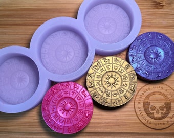 May include: Four silicone molds for casting zodiac wheel pendants. The molds are purple and have a raised design of a zodiac wheel with a sun in the center. There are three finished pendants in the image: gold, purple, and pink.