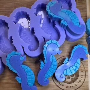 May include: Purple silicone molds for making seahorse-shaped soaps or other crafts. The molds are shown with several finished seahorse soaps in shades of blue and purple.