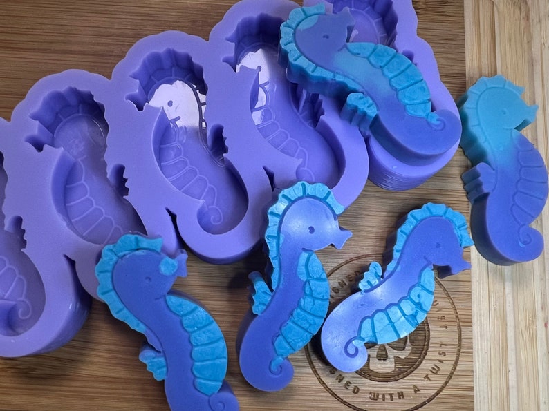 May include: Purple silicone molds for making seahorse-shaped soaps or other crafts. The molds are shown with several finished seahorse soaps in shades of blue and purple.