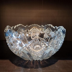 May include: A clear glass bowl with a cut glass design. The bowl has a scalloped edge and is perfect for serving fruit or snacks.
