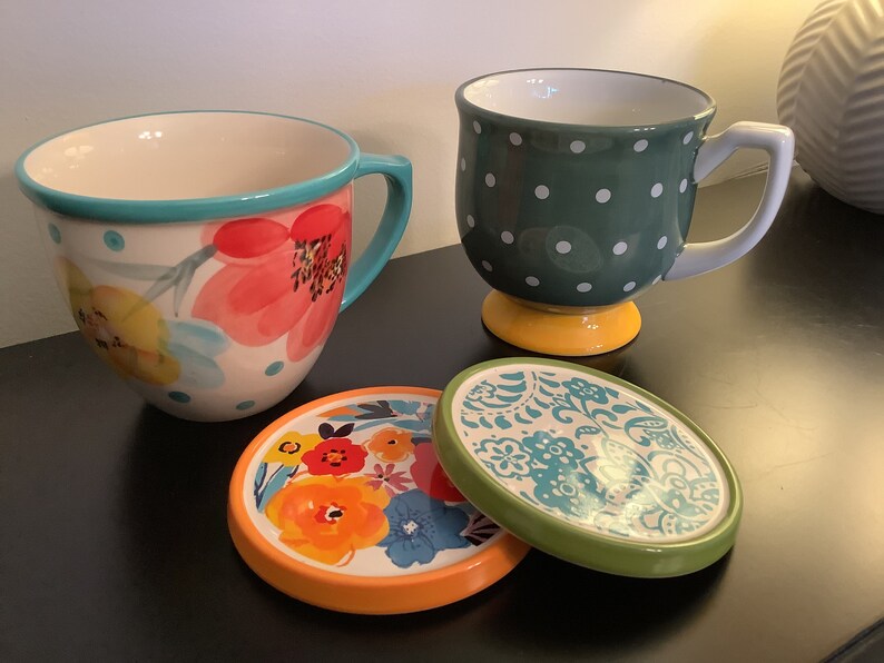 Pu&ograve; includere: Due tazze in ceramica con motivi floreali e a pois, e due sottobicchieri abbinati con motivi floreali e paisley. Le tazze e i sottobicchieri sono in tonalit&agrave; di blu, verde, giallo, arancione e rosso.