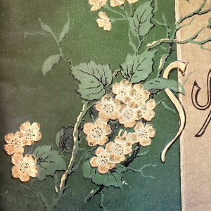 May include: A green background with a gold floral design. The flowers are delicate and have a vintage feel. The design is reminiscent of a book cover or a decorative piece.