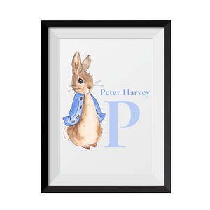May include: A framed print featuring a watercolor illustration of Peter Rabbit wearing a blue jacket, standing next to the letter P in a light blue color. The name "Peter Harvey" is written above the letter.