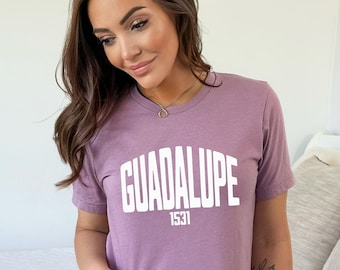 May include: A mauve t-shirt with the text "GUADALUPE 1531" in white.