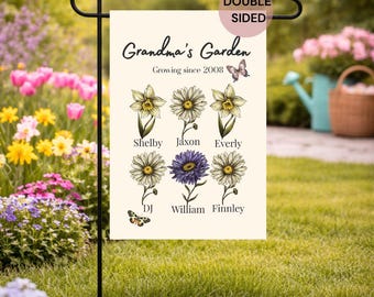 May include: A double-sided garden flag with the text "Grandma's Garden" and the phrase "Growing since 2008." The flag features illustrations of flowers and names. A black metal stand holds the flag in a garden setting.