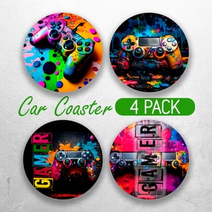 Puede incluir: Conjunto de cuatro posavasos de coche coloridos con un mando de videojuegos con salpicaduras de pintura. Los posavasos tienen un fondo negro con la palabra "GAMER" en letras blancas.