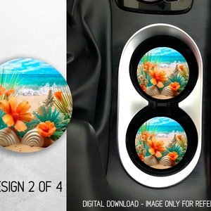 May include: Two round car coasters with a beach scene featuring orange flowers, green leaves, and white seashells on a sandy beach with blue water and white waves.  The coasters are in a car cup holder.