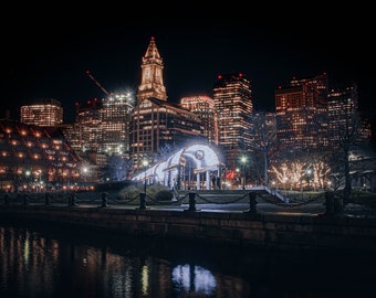 May include: A night view of a city skyline with a large, illuminated archway in the foreground. The city is lit up with lights, and the buildings are tall and modern. The archway is decorated with lights, and there are people walking through it.