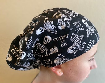 Op de afbeelding: Zwarte en witte scrub-muts met schedel- en skeletopdruk met de tekst "Coffee or Die" en "Death before Decaf".