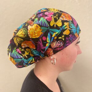 May include: A black scrub hat with a colorful butterfly print. The hat has a gathered top and a tie at the back.