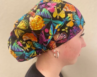 May include: A black scrub hat with a colorful butterfly print. The hat has a gathered top and a tie at the back.