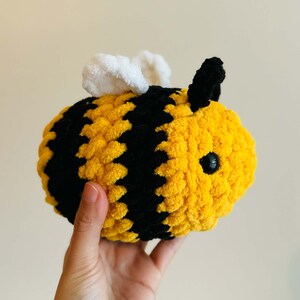 May include: A crocheted bee plush toy with yellow and black stripes, white wings, and black eyes.