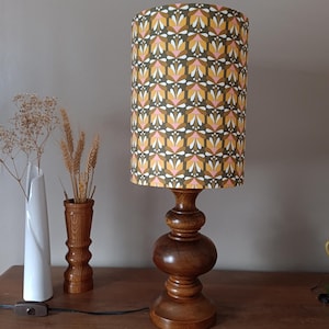 Vintage table lamp with a turned solid oak wood base, handmade lampshade in 70s floral/graphic fabric in khaki, pink, and white.