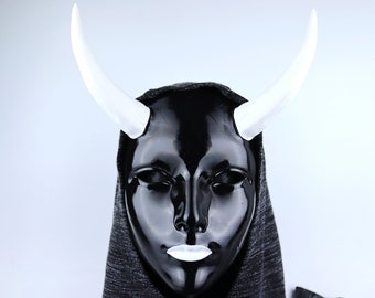 May include: A black mask with white horns, worn over a black hooded garment.
