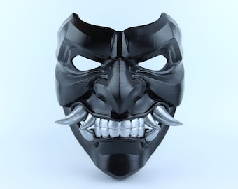 May include: A black and silver Oni mask with a fierce expression. The mask has sharp teeth and horns, and the eyes are hollow.