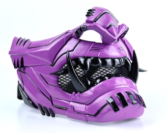 May include: A purple and black plastic mask with a geometric design. The mask has a mesh covering the eyes and a large, toothy mouth.