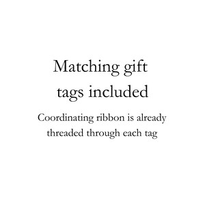 May include: A white graphic with black text that reads: Matching gift tags included. Coordinating ribbon is already threaded through each tag. The text is centered and presented in a clear, serif font against a plain white background.