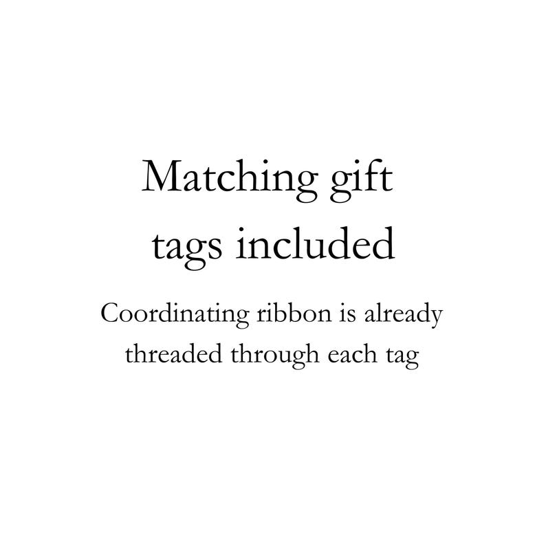May include: A white graphic with black text that reads: Matching gift tags included. Coordinating ribbon is already threaded through each tag. The text is centered and presented in a clear, serif font against a plain white background.