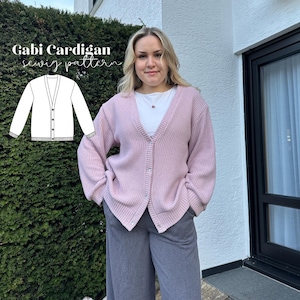 Op de afbeelding: Een lichtroze vest met een V-hals en knoopsluiting. Het vest wordt gecombineerd met een grijze broek. De afbeelding bevat ook een diagram van het "Gabi Cardigan naaipatroon".