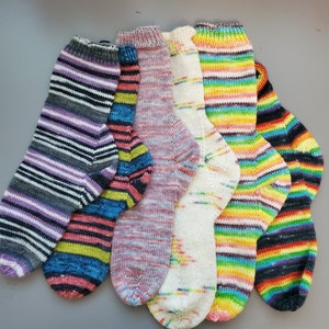 Op de afbeelding: Zes paar kleurrijke gestreepte gebreide sokken. De sokken zijn gemaakt van verschillende gekleurde garens en hebben verschillende patronen.