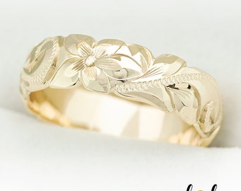May include: A gold band ring with a floral design. The ring features a carved flower with leaves and a textured finish.