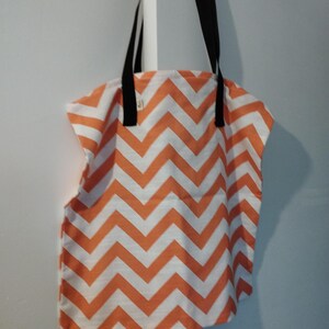 Może przedstawiać: Torba typu tote w kolorze pomarańczowym i białym z wzorem chevron i czarnymi uchwytami.