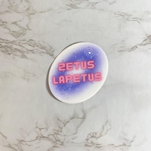 May include: A white round sticker with a purple galaxy design and the text "ZETUS LAPETUS" in pink.
