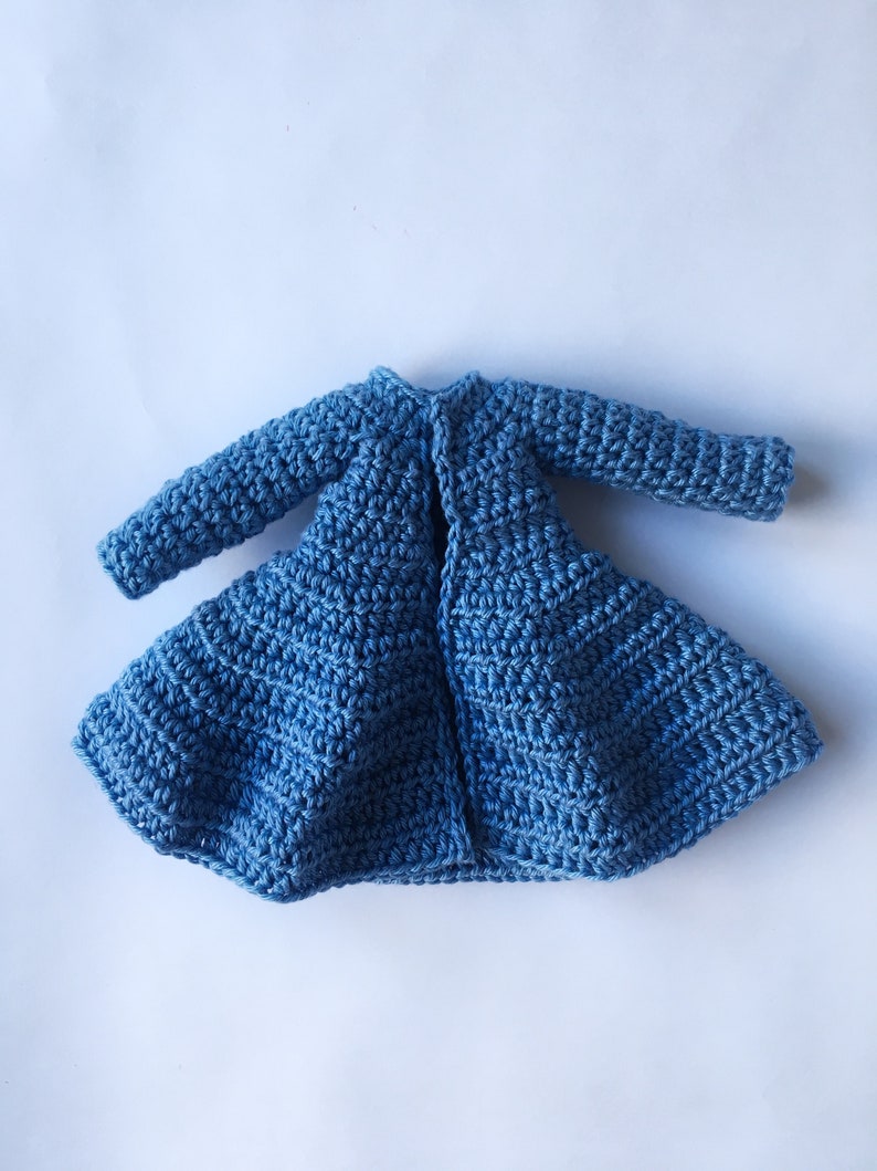 K&ouml;nnte beinhalten: Ein blauer H&auml;kelcardigan mit langen &Auml;rmeln und einem ausgestellten Saum.