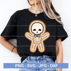 May include: A black t-shirt featuring a gingerbread skeleton wearing a blue bow tie. The gingerbread skeleton has a skull head with a smiling face. The text "PNG - SVG - JPG - DXF" is at the bottom of the image.