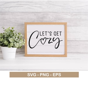 Puede incluir: Un cartel enmarcado en blanco con texto negro que dice "Let's Get Cozy" con un pequeño corazón en la palabra "Cozy".