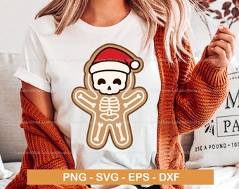 Pode incluir: Uma camiseta branca com um design de homem de gengibre. O homem de gengibre está usando um chapéu de Papai Noel vermelho e tem um design de esqueleto. O texto "PNG - SVG - EPS - DXF" é impresso abaixo do design.