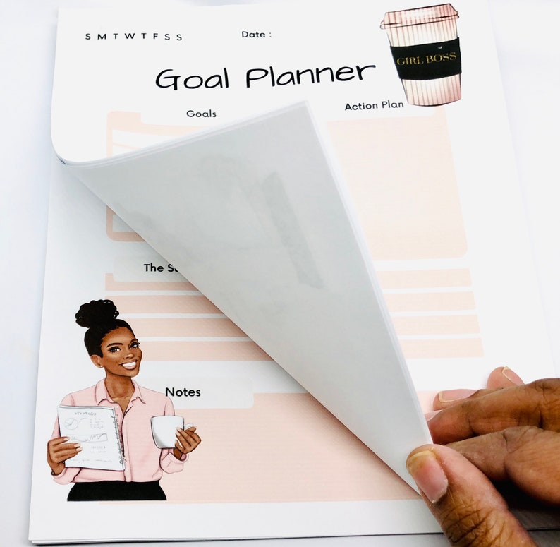 Peut inclure: Un planificateur de buts rose et blanc avec une illustration de tasse &agrave; caf&eacute; qui dit "Girl Boss". Le planificateur comporte des sections pour les objectifs, le plan d'action et les notes. Une femme &agrave; la peau fonc&eacute;e est illustr&eacute;e tenant une tasse &agrave; caf&eacute; et un planificateur.