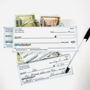 May include: Two blank checks with the name "ManifestBank" printed on them. The checks are lying on top of a pile of US dollar bills. One check has a handwritten amount of $10,000.00 and the date July 1st, 2024.