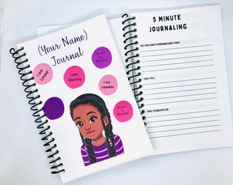 May include: A white journal with a black spiral binding. The cover features a cartoon illustration of a young Black girl with purple and pink accents. The journal has the text "(Your Name) Journal" and includes positive affirmations such as "I am Loved", "I am Worthy", "I am Smart", "I am Capable", "My Skin is Beautiful", and "My Hair is Beautiful". The opposite side of the journal has the text "5 Minute Journaling" and includes prompts for journaling.