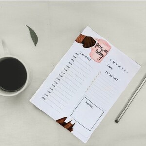 May include: A white planner with a pink and brown illustration of a hand holding a mug with the text "focus on today". The planner has sections for a schedule, to-do list, and notes.