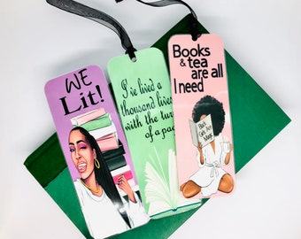 May include: Three colourful bookmarks featuring illustrations of women with text that reads "We Lit!" "I've lived a thousand lives with the turn of a page" and "Books & tea are all I need".
