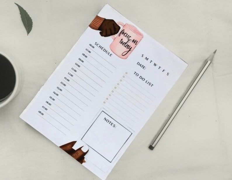 May include: A white daily planner with a pink coffee cup illustration and the text "focus on today". The planner has a schedule section, a to-do list, and a notes section.
