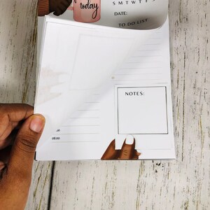 May include: A white daily planner with a to-do list, notes section, and a calendar. The planner has a pink and white illustration of a hand holding a coffee mug with the text "focus on today".