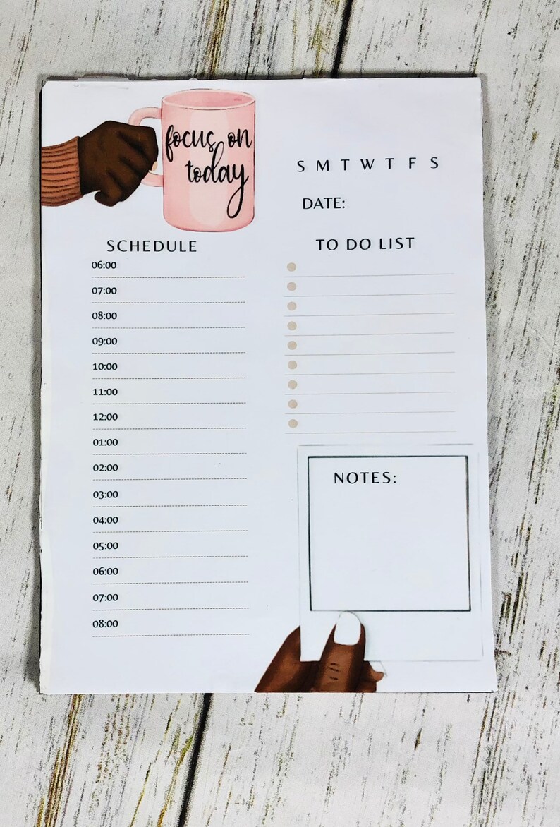 May include: A white dry-erase board with a daily schedule, to-do list, and notes section. The board has a pink mug with the text "focus on today" and a hand holding the mug.