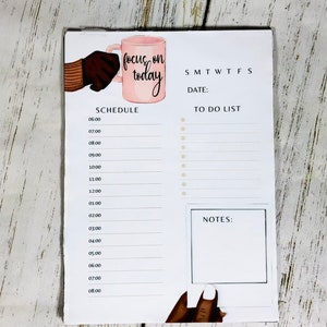 May include: A white dry erase board with a pink mug illustration and the text "focus on today". The board has a daily schedule, a to-do list, and a notes section.