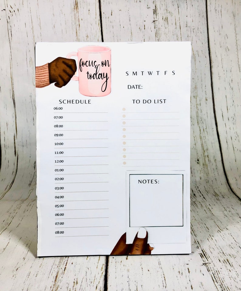 May include: A white daily planner with a pink coffee cup illustration and the text "focus on today". The planner has a schedule section with times from 6:00 AM to 8:00 PM, a to-do list section, and a notes section.