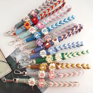 Op de afbeelding: Een verzameling kleurrijke macramé polsbandjes met metalen karabijnsluitingen. Elk bandje heeft een gevlochten ontwerp in verschillende kleuren, geaccentueerd met een bloemvormig macramé detail. Geschikt voor sleutels of kleine accessoires.