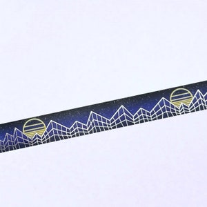Op de afbeelding: Washi tape met een herhalend patroon van een sterrenhemel met witte geometrische bergen en een gele zon.