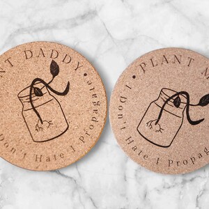 May include: Two cork coasters with a plant in a jar design. The text on the coasters reads "Plant Daddy I Don't Hate To Propagate" and "Plant Mama I Don't Hate To Propagate".